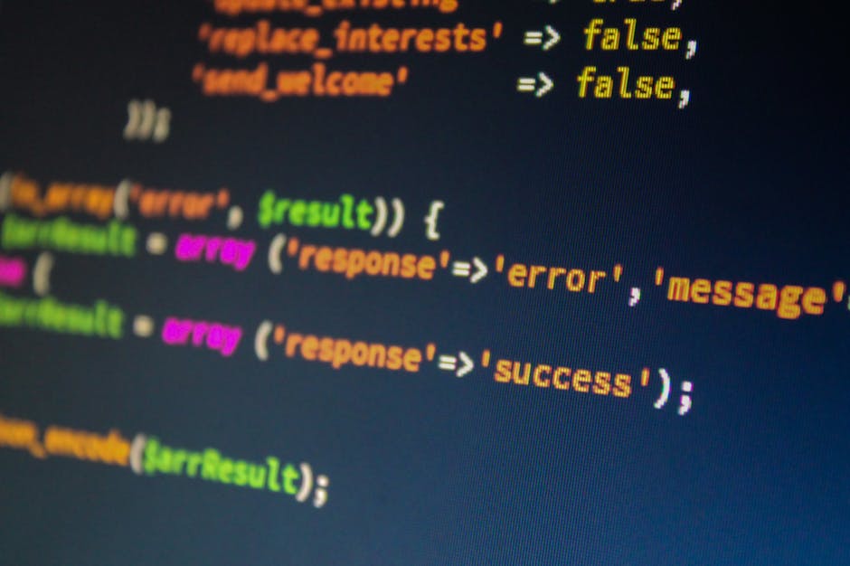 A close-up digital photograph displaying colorful lines of programming code on a computer screen. The code appears to be JavaScript, with keywords and syntax highlighted in yellow, orange, pink, green